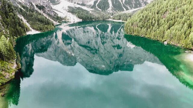 Vue a&eacute;rienne cin&eacute;matique du lac de Braies avec les reflets des montagnes des Dolomites et ses barques en bois