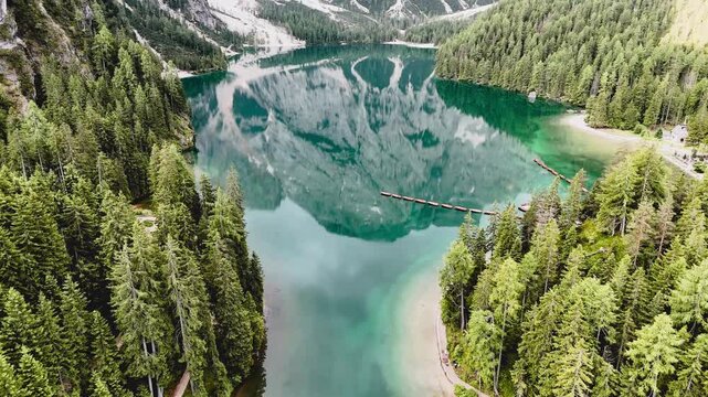 Vue a&eacute;rienne cin&eacute;matique du lac de Braies avec les reflets des montagnes des Dolomites et ses barques en bois