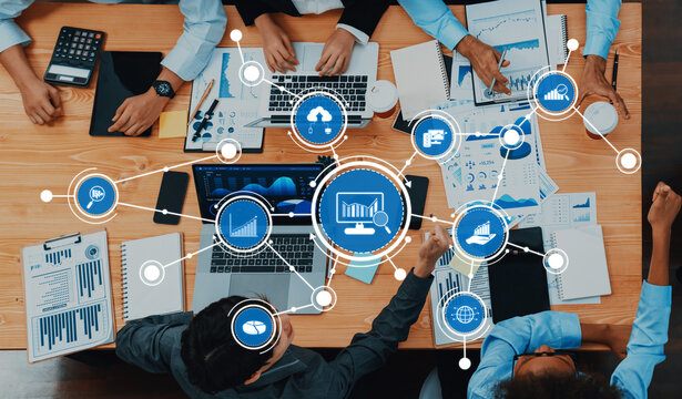 This image captures a dynamic business analytics session, showcasing professionals collaborating over laptops and reports, surrounded by visual data insights and graphs. Amity - Powered by Adobe