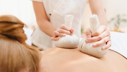 Close-up of a person receiving a relaxing massage with herbal compresses. Massage therapy focuses on relaxation and wellness. Herbal compress massage technique. Spa and wellness session.