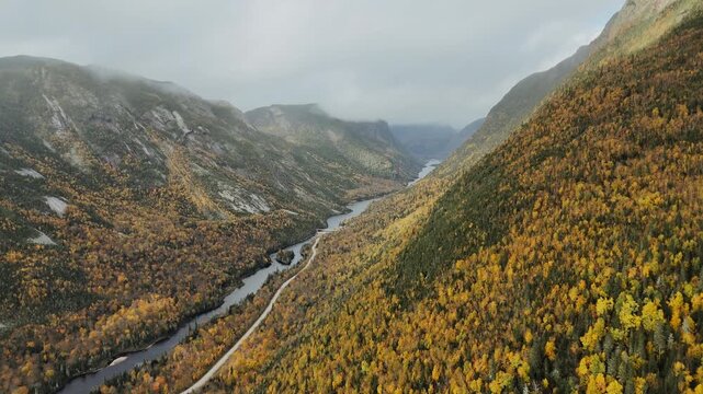 Vid&eacute;o de drone d'un paysage spectaculaire d'une rivi&egrave;re au creux d'une vall&eacute;e glaciaire sous la brume automnale, for&ecirc;t bor&eacute;ale color&eacute;e, Quebec Canada