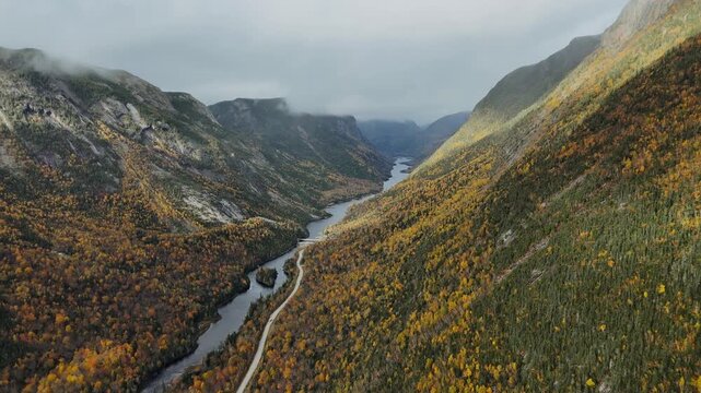 Vid&eacute;o de drone d'un paysage spectaculaire d'une rivi&egrave;re au creux d'une vall&eacute;e glaciaire sous la brume automnale, for&ecirc;t bor&eacute;ale color&eacute;e, Quebec Canada