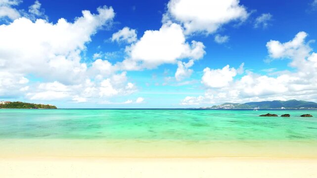 Tropical landscape of blue sea waving by the white beach and floating a clouds in the blue sky in summer, Okinawa in Japan