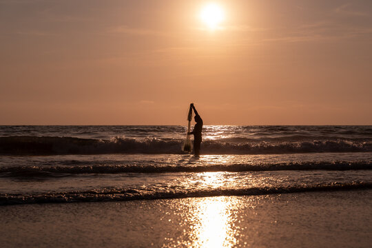 Fisherman throwing a cast net or atarraya at the seashore with water at his waist. Artisanal fishing with a throw net. costalegre