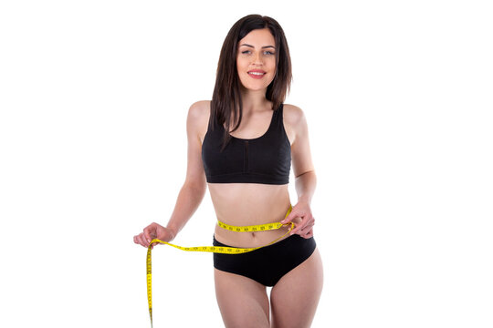 Fit woman measuring waist and hips with tape wearing black sportswear isolated on white