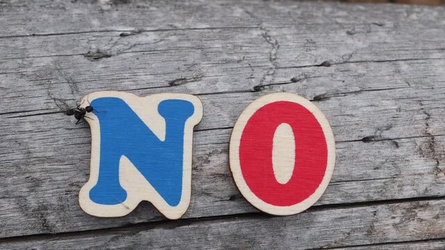 Blue and red wooden NO letters on log. Ideal for concepts of refusal, prohibition, disagreement, or negative responses.