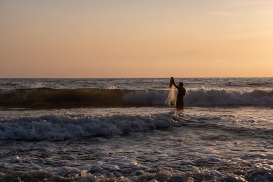 Fisherman throwing a cast net or atarraya at the seashore with water at his waist. Artisanal fishing with a throw net. costalegre