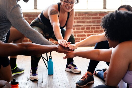 Group of diverse people, including African American, in workout placing hands together in a team. Workout, team, diverse, and fitness. Exercise for better health. Team stacking hands together.