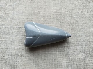 Smooth Gray Stone Sculpture with Cracks on Neutral Textured Surface