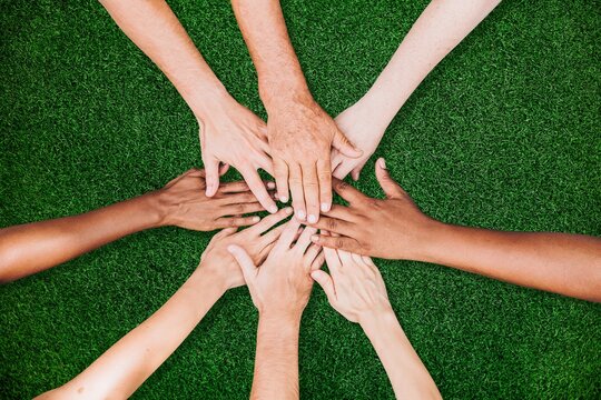 People stacking hands together in the park