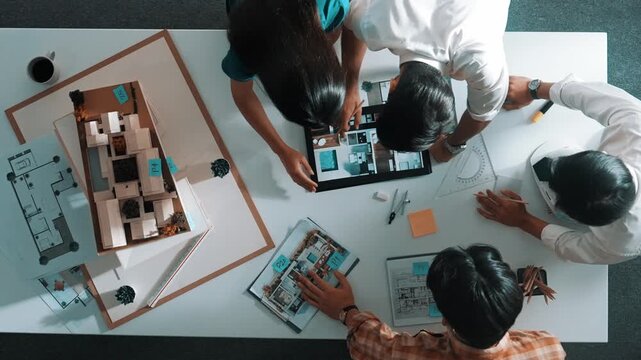 Time lapse of designer looking at model while discussing about building. Top view of architect engineer explaining idea while talking and writing blue print scattering at meeting table. Alimentation.