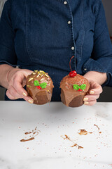 A pastry chef holding two small panettone cakes covered in melted chocolate_vertical.