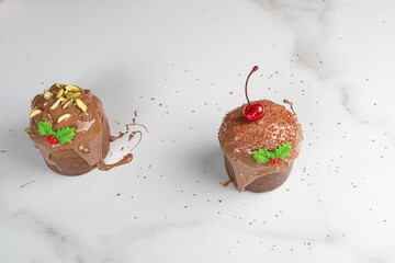 Two small panettone cakes covered in melted chocolate, pistachios, cherrie, and caramel crunch.