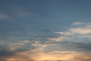 Beautiful sunset sky with soft cirrus clouds illuminated by golden light at twilight.