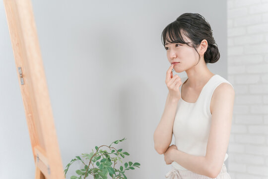 Asian woman looking in the mirror suffering from chapped lips, herpes and mouth ulcers