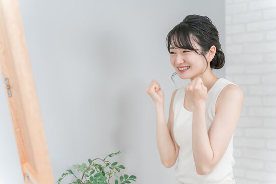 A smiling Asian woman pumping her fist after successfully dieting and losing weight