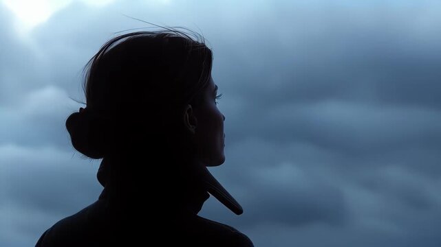 Silhouette of Contemplation: Silhouette of a woman standing and looking up at the sky in a moment of thoughtful reflection against a backdrop of brooding clouds, captured with striking detail. 