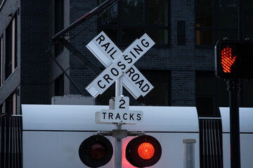 Sound transit light rail commuter train crossing, railroad crossing sign, white X, multiple tracks, yield to train red light flashing, transportation background

