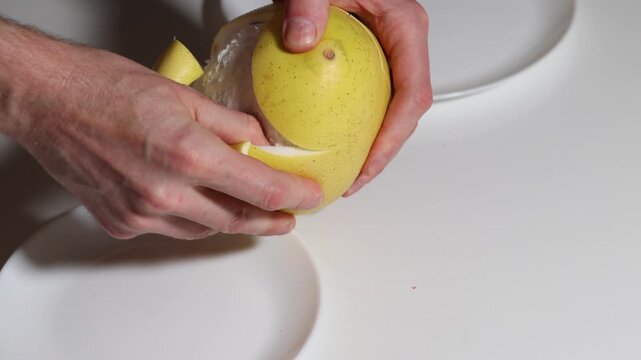 Close-up showcases hands peeling a pomelo on a white table, revealing juicy fruit, preparing a healthy snack, emphasizing fruit texture, suggesting healthy eating habits