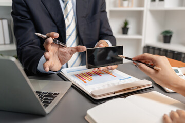 A collaborative startup meeting showing professionals reviewing financial charts and discussing strategic ideas in a modern office setting.