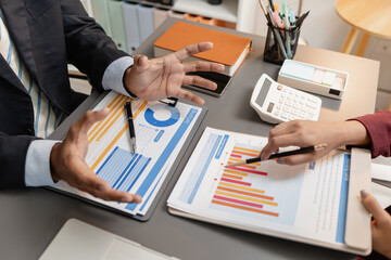 A business meeting scene where professionals review financial charts and exchange insights, highlighting strategic planning and collaborative decision making in a modern office environment.