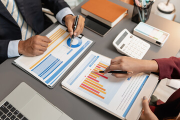 A business meeting scene where professionals review financial charts and exchange insights, highlighting strategic planning and collaborative decision making in a modern office environment.