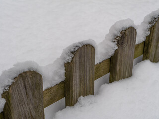 Snow-covered wooden fence in a quiet winter landscape. Minimal rustic composition with soft light, natural textures, and clean copy space, ideal as a seasonal background or nature concept