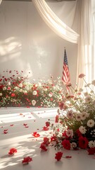 Patriotic floral arrangement with American flag and scattered rose petals in a sunlit room, celebrating a national holiday or memorial.