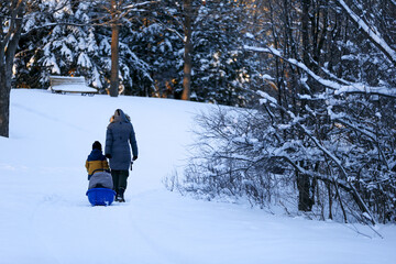 Une mère et son fils marchent dans la neige par une journée d'hiver ensoleillée.