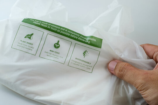 Hand holding eco friendly biodegradable plastic bag with sustainability labels. Perfect for sustainability campaigns, eco education, green business content, waste reduction, and green lifestyle