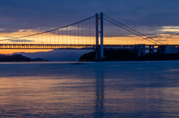 Obraz premium ブルーアワーの吊り橋、灯りが映る海