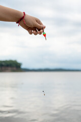 Hand Holding Fishing Float Over Lake © LUJO