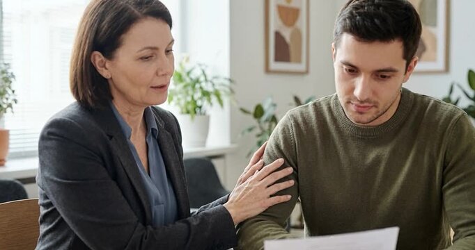 Woman comforting man indoors document examination close up
