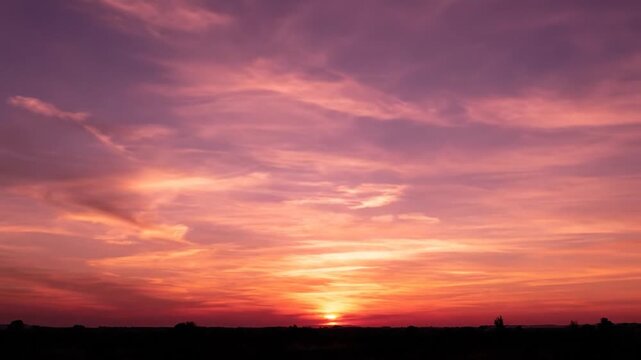 A vibrant sunset over a silhouetted landscape, showcasing shades of pink, purple, and orange
