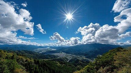Vibrant Sky Over Mountainous Landscape: The Sun casts brilliant rays across a vivid blue sky dotted with fluffy clouds, illuminating a breathtaking vista of mountains and valleys.