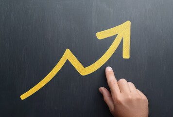 Hand Drawing Yellow Arrow on Chalkboard Representing Growth and Progress in Business and Education