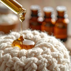 Amber liquid drips from pipette onto textured white fabric; jars in background