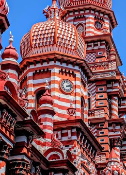Low-angle view of a historic red and white mosque with intricate architectural details under a clear blue sky in Colombo, Sri Lanka.