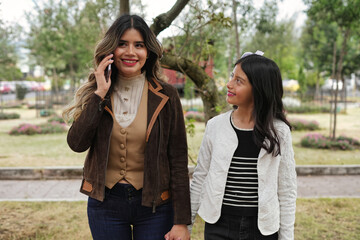 Woman talking on smartphone walking with girl outdoors