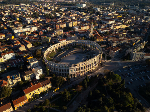 High altitude aerial view of Pula Arena and old town rooftops at sunset, Croatia
