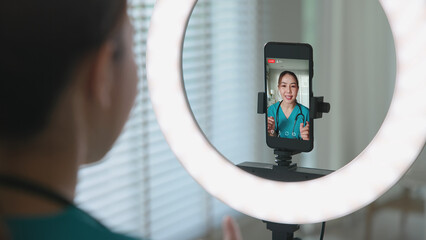 Young adult woman Gen Z asia people anti aging expert modern nurse live talk viral video selfie camera on mobile phone app mental health care. Online sharing digital virtual asian vlogger filming.
