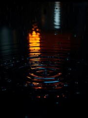 Raindrops creating ripples on a dark, reflective water surface at night,  reflective,  dark