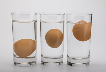 Eggs in water test on transparent glass , Egg freshness test on white background , Bad egg floats in water © Suttiwan