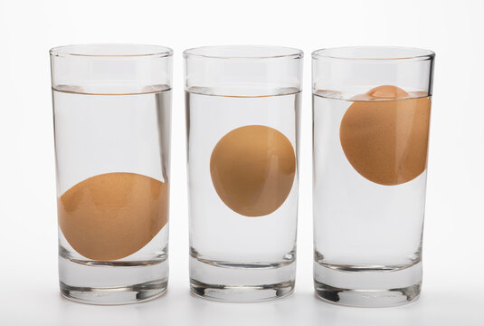 Eggs in water test on transparent glass , Egg freshness test on white background , Bad egg floats in water