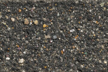 Close Up of Black Sand Texture with Small Stones and Shell Fragments Under Bright Sunlight on Coastal Shoreline Surface