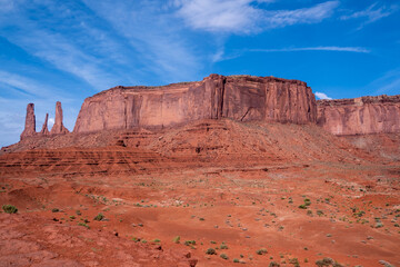 Fototapeta premium A desert landscape with a large red rock formation in the background