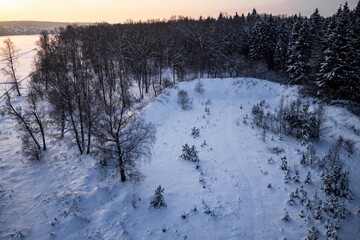 Drone shot: neglected snow-draped shooting range, undulating earthen berms. Pristine winter vista...