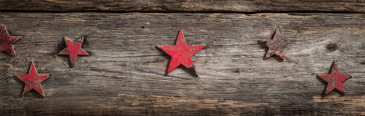 Rustic wooden background with distressed red star-shaped accents and textured grain surface for vintage or patriotic-themed designs