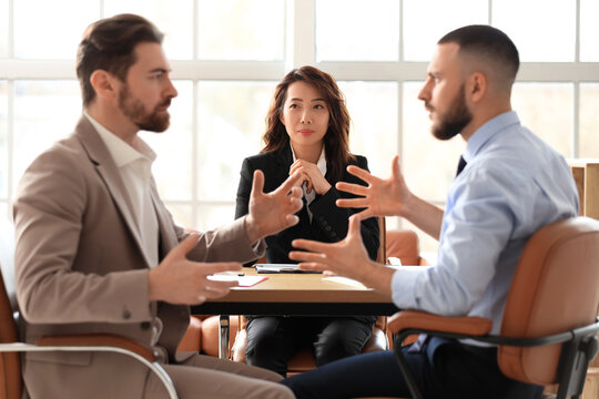 Female Asian court mediator working with clients at table in office