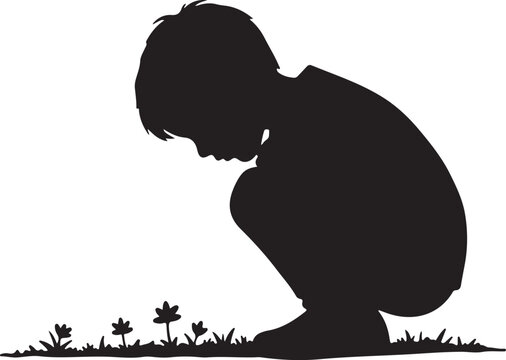 Silhouette of a child kneeling in a grassy field